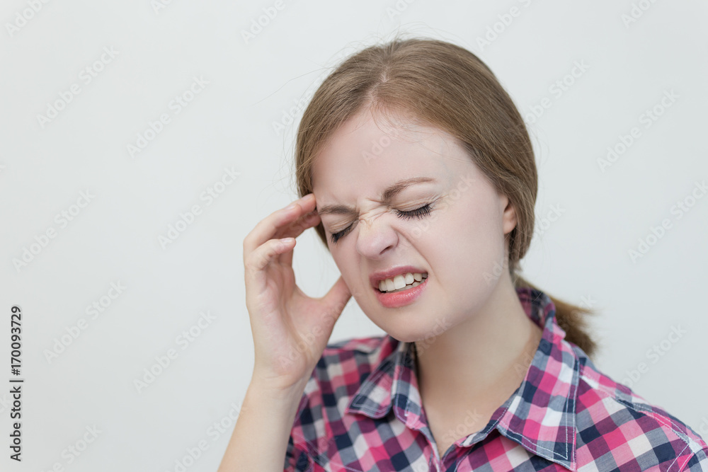 Young caucasian woman because of a headache keeps fingers on temples Young caucasian woman because of a headache keeps fingers on temples