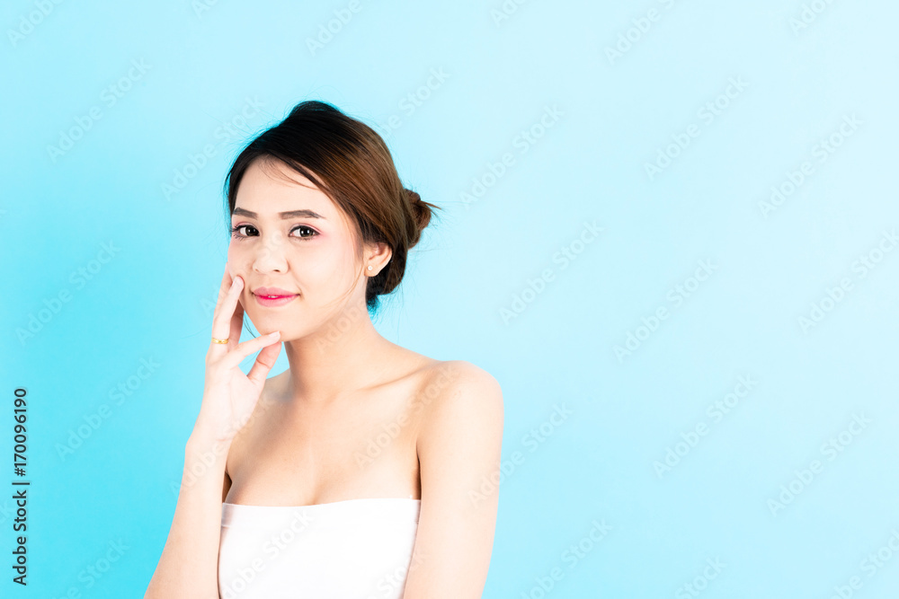 Asian young beautiful confidence woman smiling portrait touching her face over blue background. Asian young beautiful confidence woman smiling portrait touching her face over blue background.