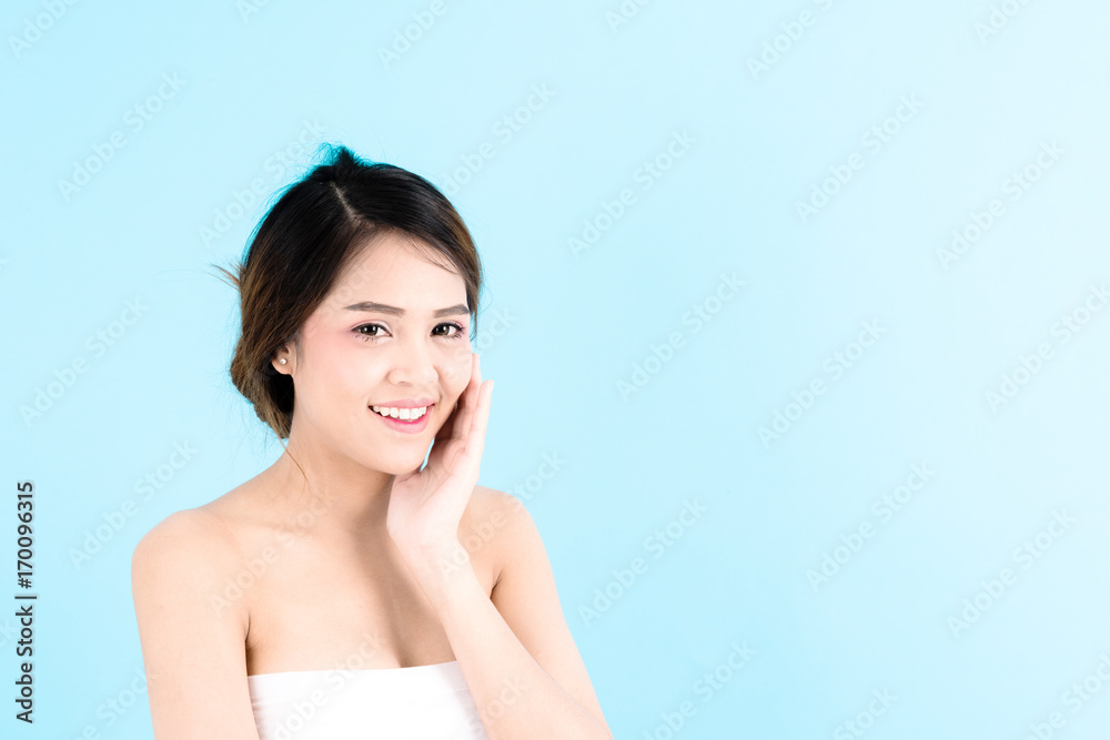 Asian young beautiful confidence woman smiling portrait touching her face over blue background. Asian young beautiful confidence woman smiling portrait touching her face over blue background.