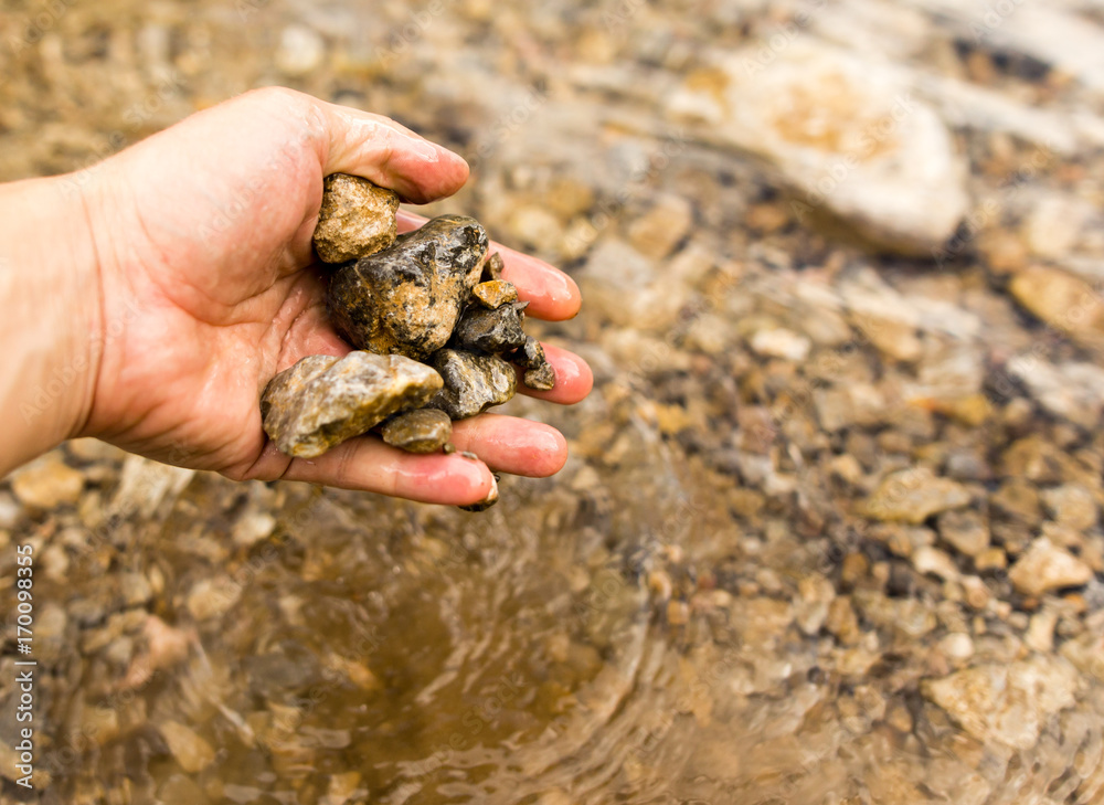 Small stones in the hand on the pond