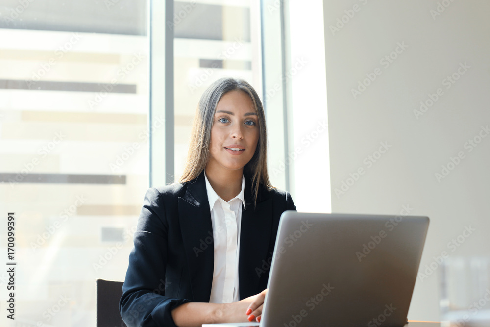 Happy businesswoman working on the laptop at office. Happy businesswoman working on the laptop at office.