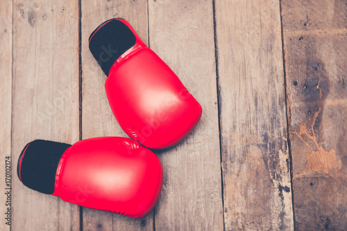 Top down view of red boxing gloves on old wood floor with vintage retro filter.