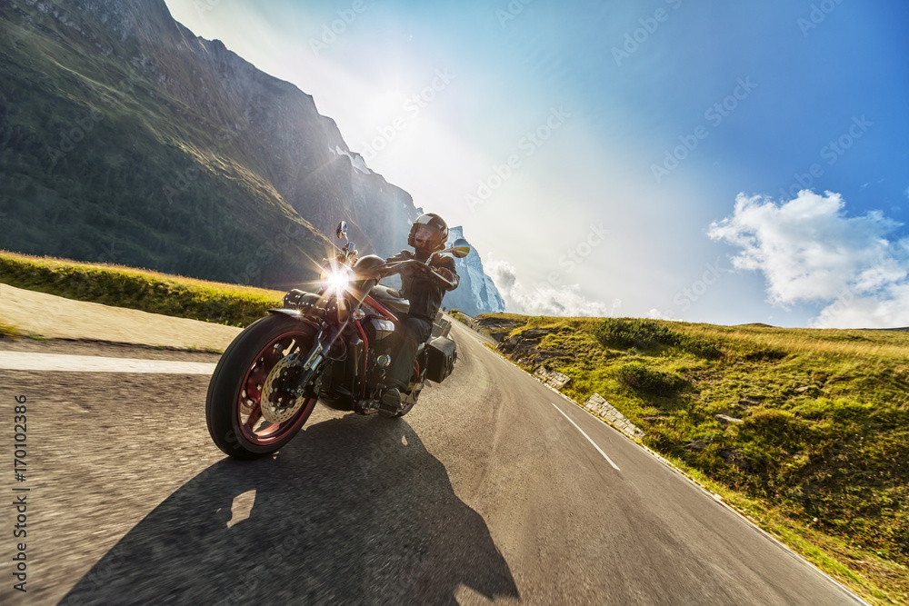 Fototapeta premium Kierowca motocykla jedzie na autostradzie alpejskiej. Fotografia plenerowa