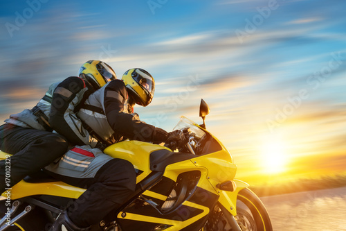 Motorbikers on sports motorbike riding in sunset photo