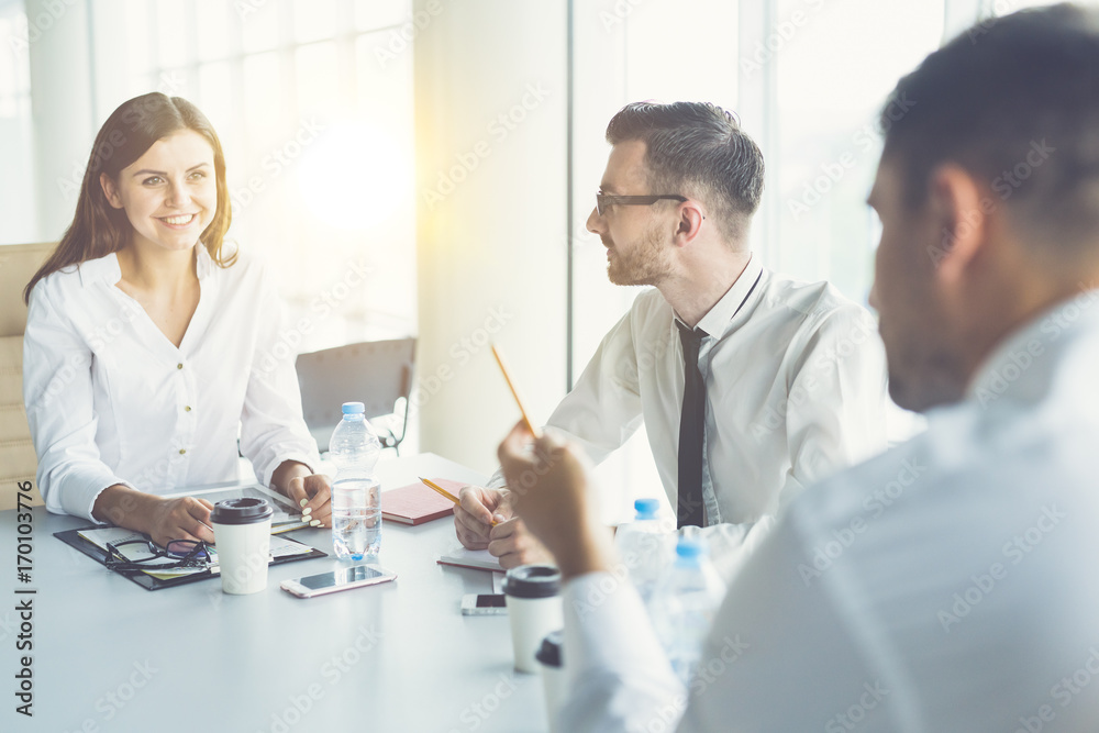Fototapeta premium The three business people talk at the table on the sun background