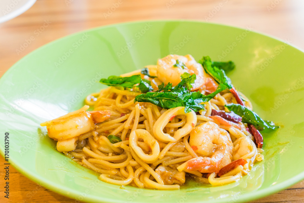 Spicy Spaghetti Seafood in a green plate on wooden background Spicy Spaghetti Seafood in a green plate on wooden background