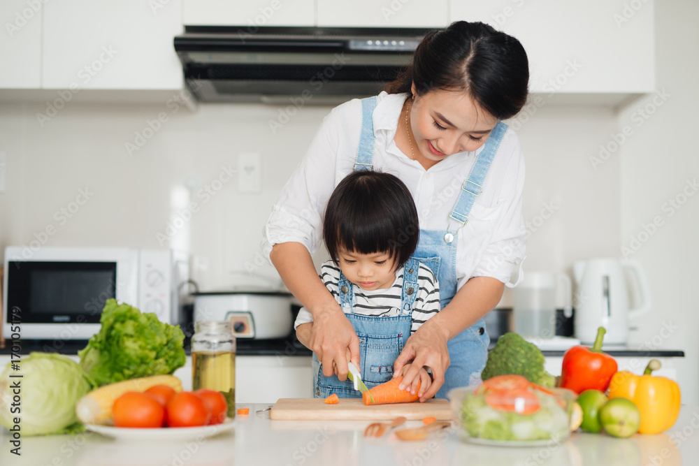 Happy family in the kitchen. Mother and child daughter are preparing the vegetables and fruit. Happy family in the kitchen. Mother and child daughter are preparing the vegetables and fruit.