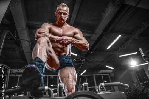 Handsome model young man training legs in gym