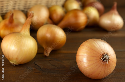 Raw onion on a wooden table and basket