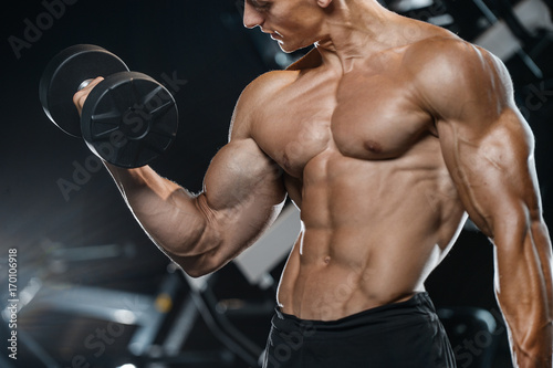 Handsome model young man training arms in gym