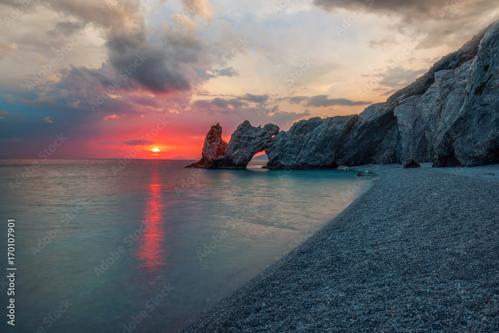 Kiesstrand am Mittelmeer mit Felsen bei dramatischen Sonnenaufgang