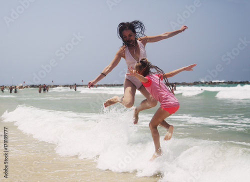 Portrait of happy  real beautiful young girls jumping on seaside photo