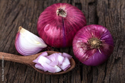 Close up of the sliced red onion and whole bulb onion on a wooden background