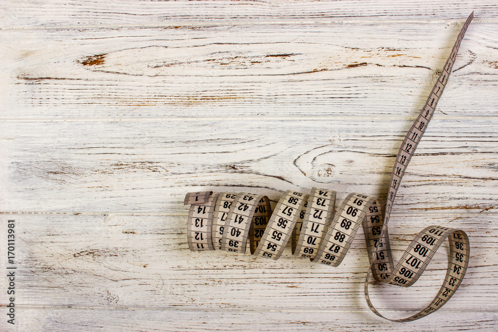 Close up tailor measuring tape on wooden table background. White measuring tape shallow dept of field. Close up tailor measuring tape on wooden table background. White measuring tape shallow dept of field.