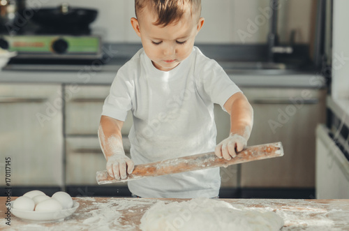 A child with a rolling pin at the table photo