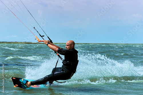 Man riding a kite surfing on the waves in the summer.