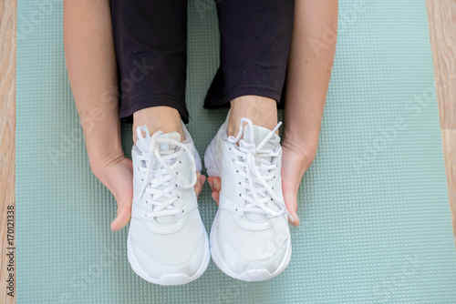 Closeup of female hands covering white sneakers