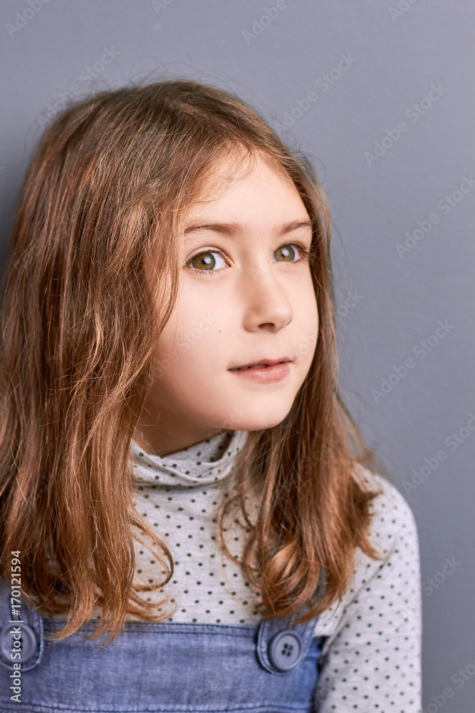 Portrait of thinking little girl indoor. Studio shot of pretty little positive girl looking away close up. Kids facial expressions.