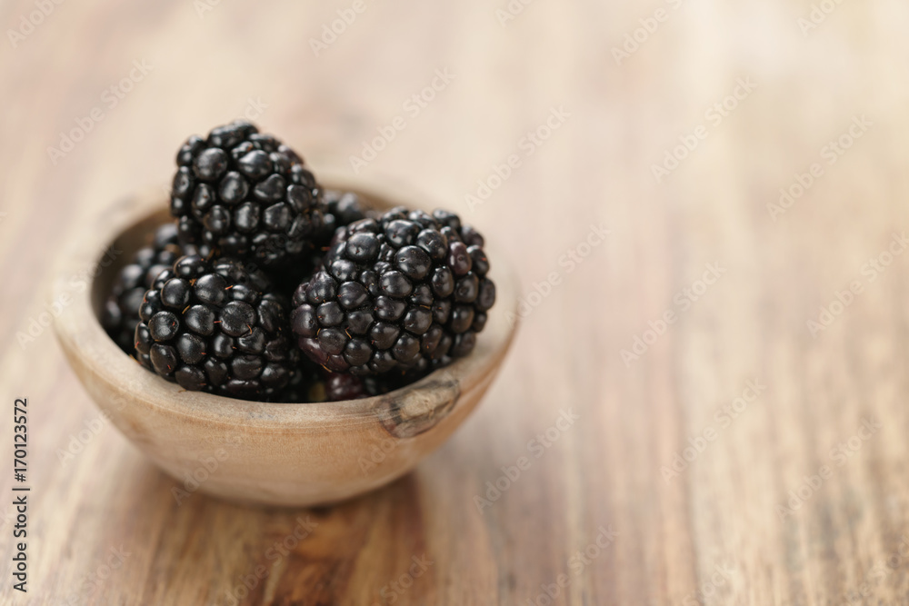 blackberries in small wood bowl on wooden table blackberries in small wood bowl on wooden table