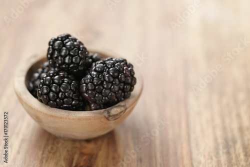 blackberries in small wood bowl on wooden table
