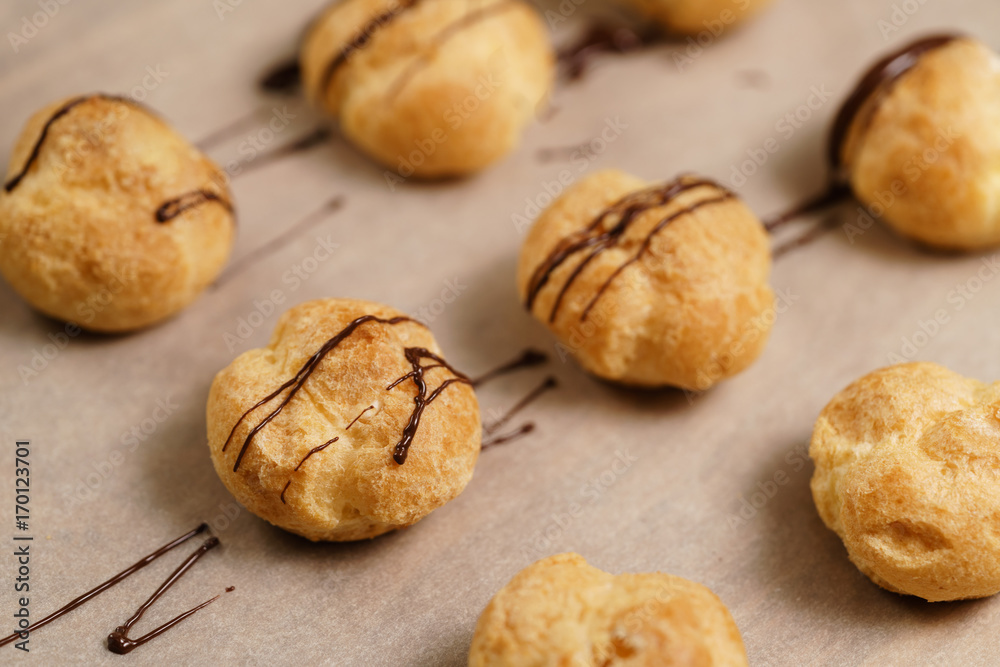 profiteroles decorated with dark chocolate on brown paper closeup