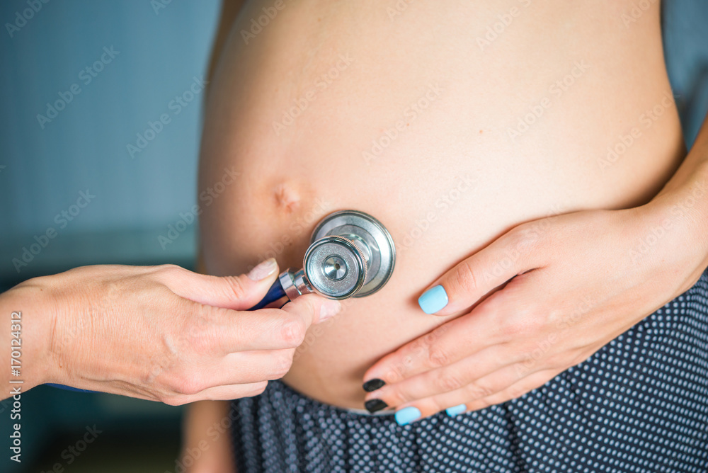 Fototapeta premium A family doctor listens with a phonendoscope for breathing, a pregnant heartbeat, a health check