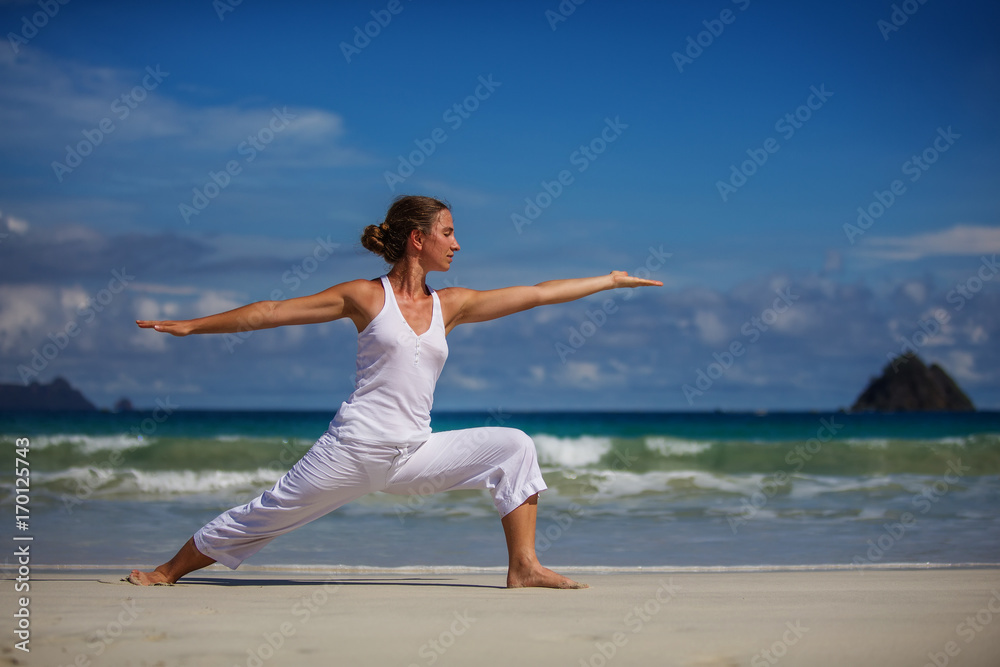 Caucasian woman practicing yoga at seashore of tropic ocean Caucasian woman practicing yoga at seashore of tropic ocean