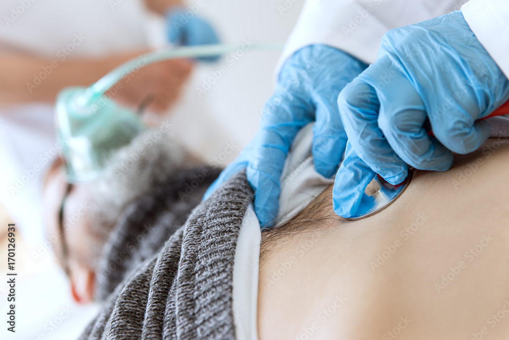 Fototapeta premium Patient in der Intensivstation, Beatmung und Untersuchung mit dem Stethoskop