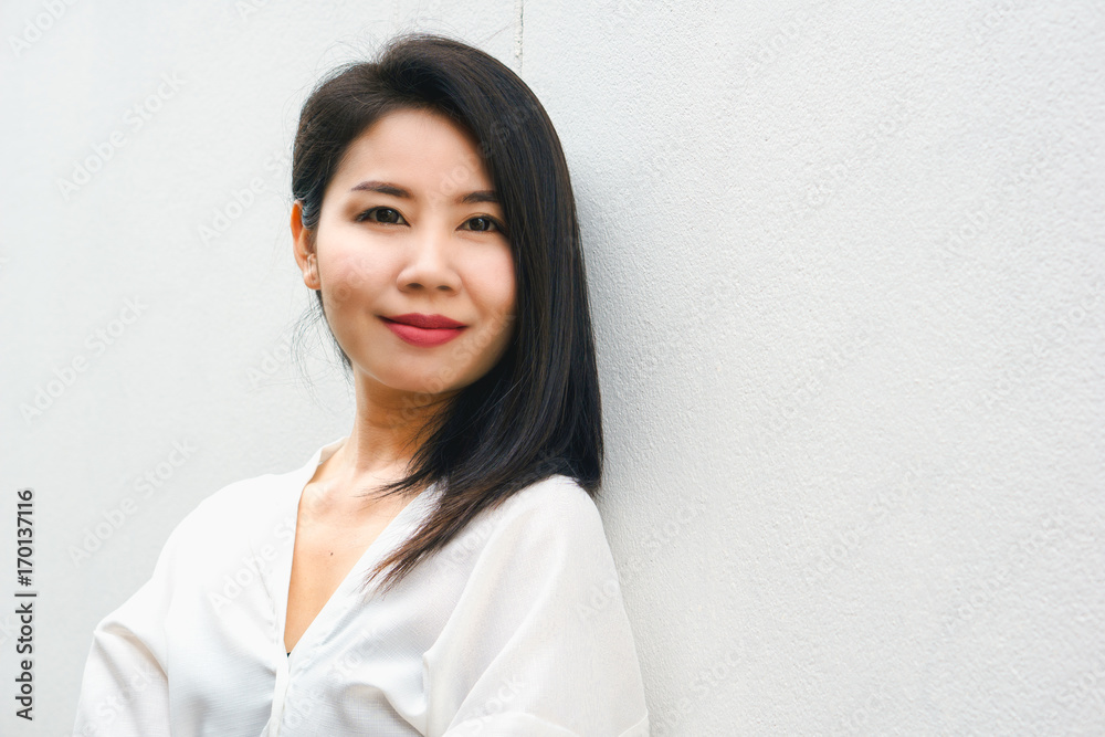 portrait of beautiful Asian business woman standing against white wall background smiling at camera portrait of beautiful Asian business woman standing against white wall background smiling at camera