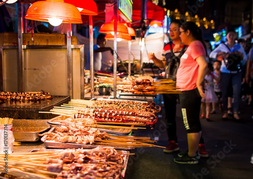 NANNING, CHINA - JUNE 9, 2017: Food on the Zhongshan Snack Street, a food market in Nanning with many people bying food and walking around