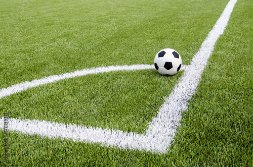 The soccer football in the corner on the artificial green grass field