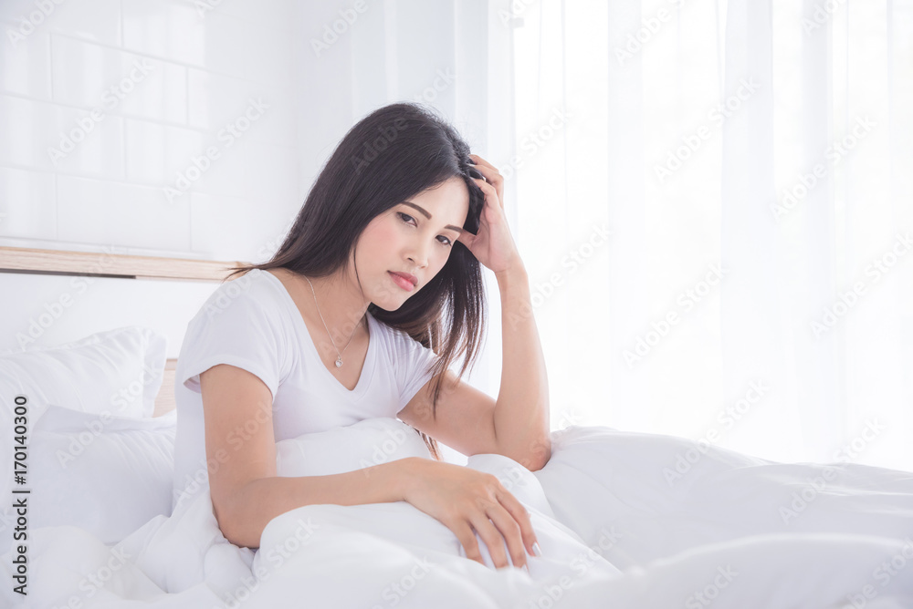 Beautiful asian woman sitting on bed with serious face in the morning Beautiful asian woman sitting on bed with serious face in the morning
