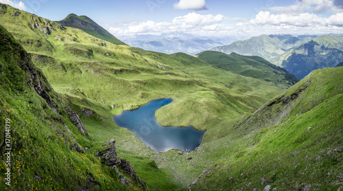 Mountain landscape with green pastures and lake in the alps