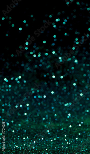 green Sparkling Lights Festive background with texture. Abstract Christmas twinkled bright bokeh defocused and Falling stars. Winter Card or invitation.