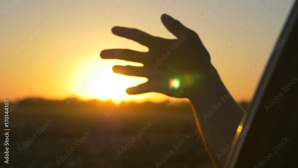 Hand at sunset. A man's hand from the window of a car in the sun's rays Hand at sunset. A man's hand from the window of a car in the sun's rays