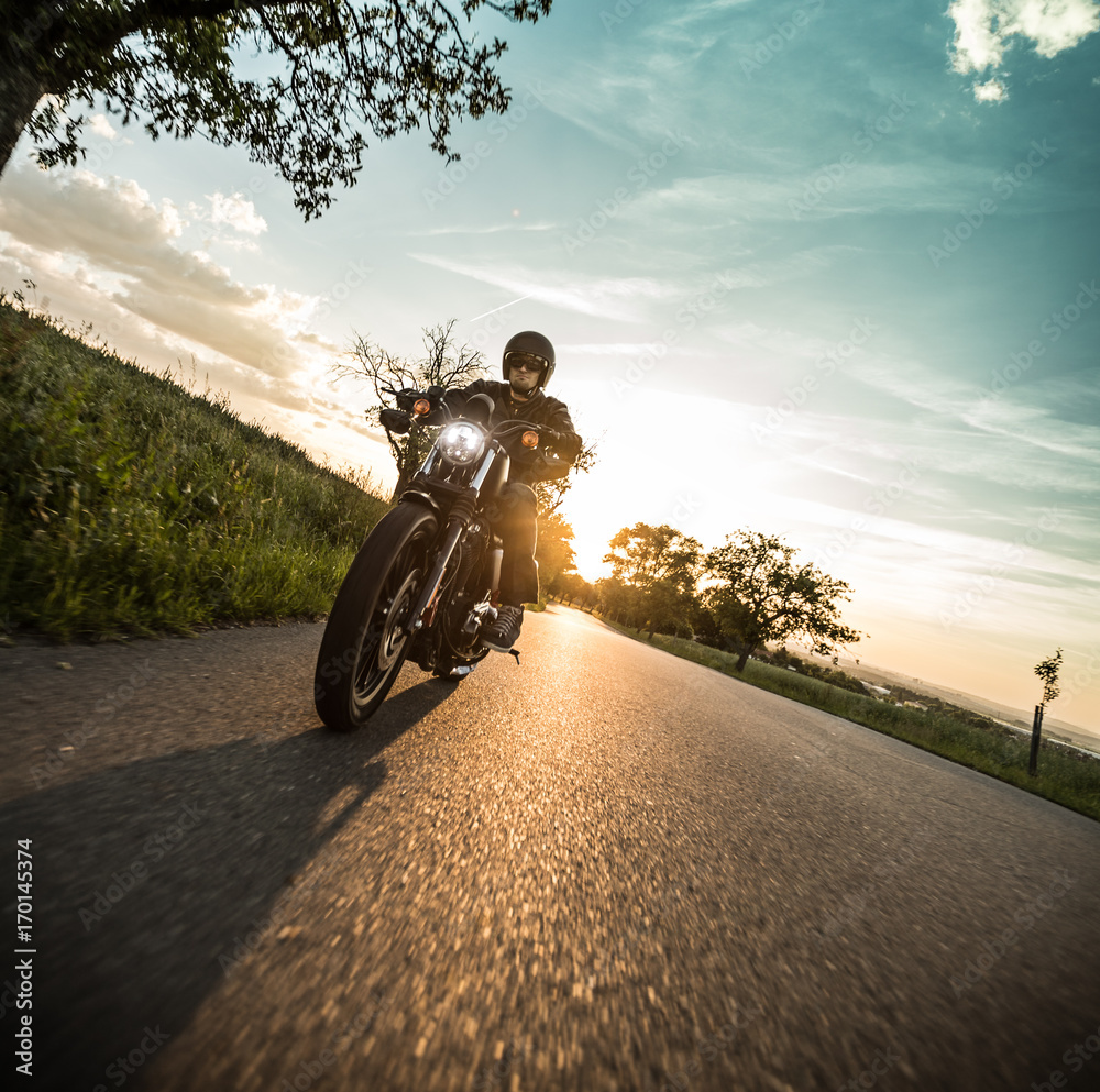 Fototapeta premium Mężczyzna jedzie motocykl sportster podczas zachodu słońca.