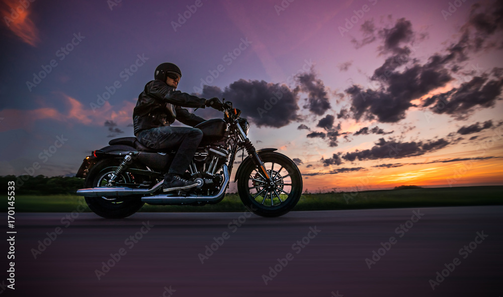 Naklejka premium Mężczyzna jedzie sportster motocykl podczas zmierzchu.