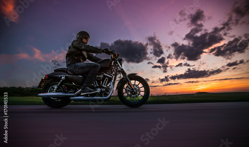 Obraz na plátně Man riding sportster motorcycle during sunset.