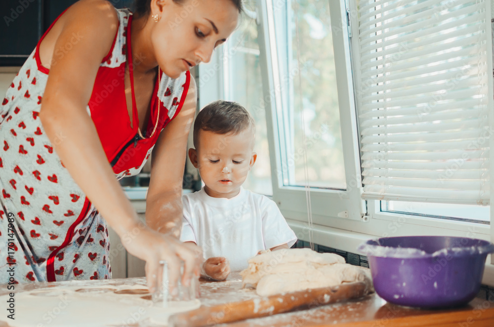 Little boy with mom in the kitchen preparing dough Little boy with mom in the kitchen preparing dough
