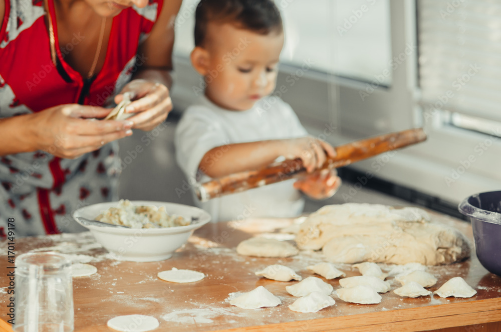 Little boy with mom in the kitchen preparing dough