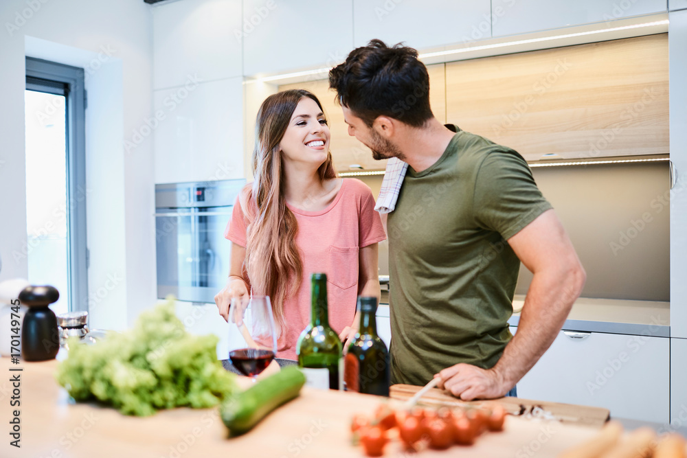 Attractive loving couple in the kitchen together, preparing meal for themselves