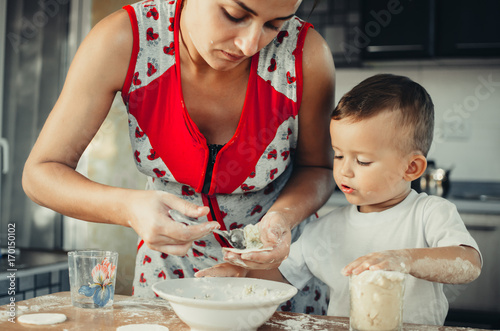 Little boy with mom in the kitchen preparing dough