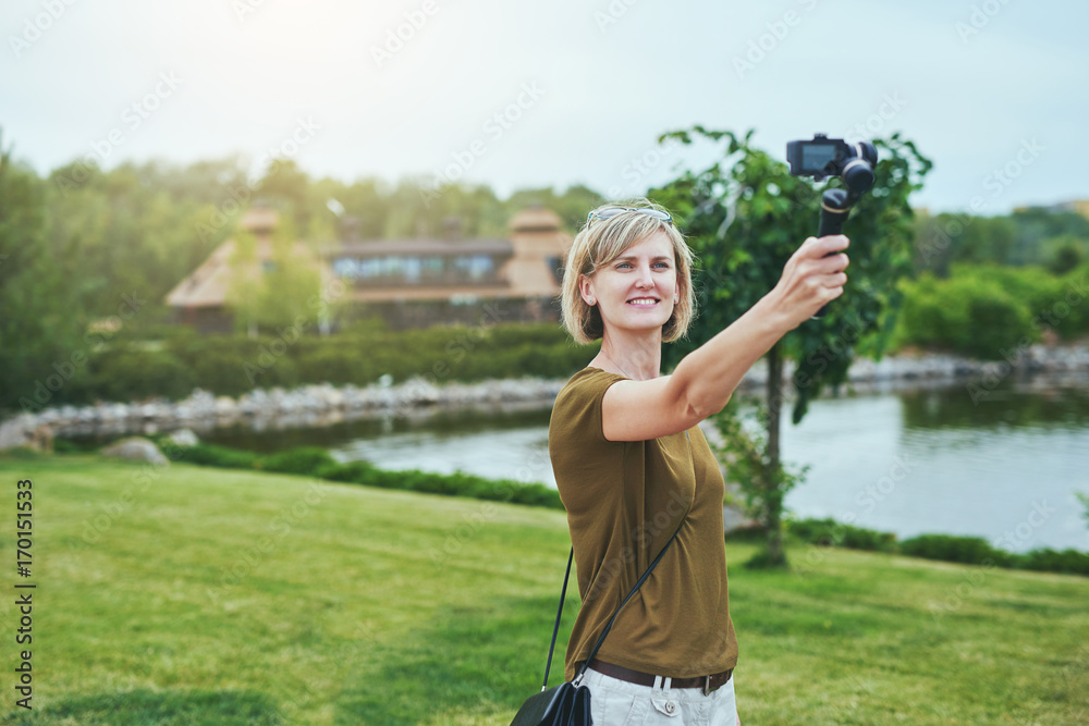 Woman capturing herself with small personal camera in a park Woman capturing herself with small personal camera in a park