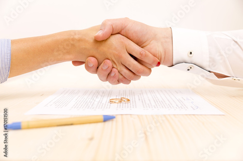 Closeup of a young man an a young woman shaking hands after signing a prenuptial agreement