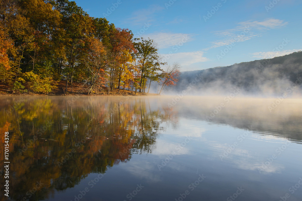 autumn sunrise over foggy lake with colorful foliage reflection with blue sky autumn sunrise over foggy lake with colorful foliage reflection with blue sky
