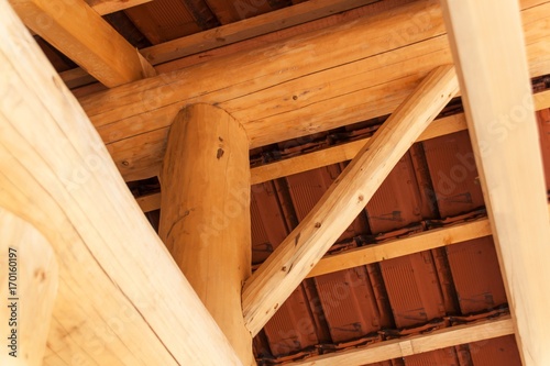Wooden beams under a red brick roof during. Detail of wooden roof structure.