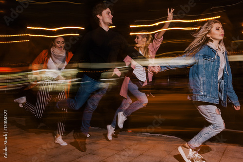 Youth movement in night city. Blurred background. Friends party, happy students outdoors, strong friendship