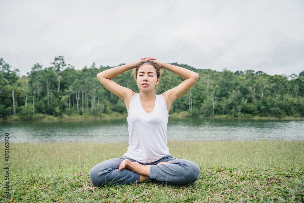 Asian women relax in the holiday. Play if yoga. on a green pasture.