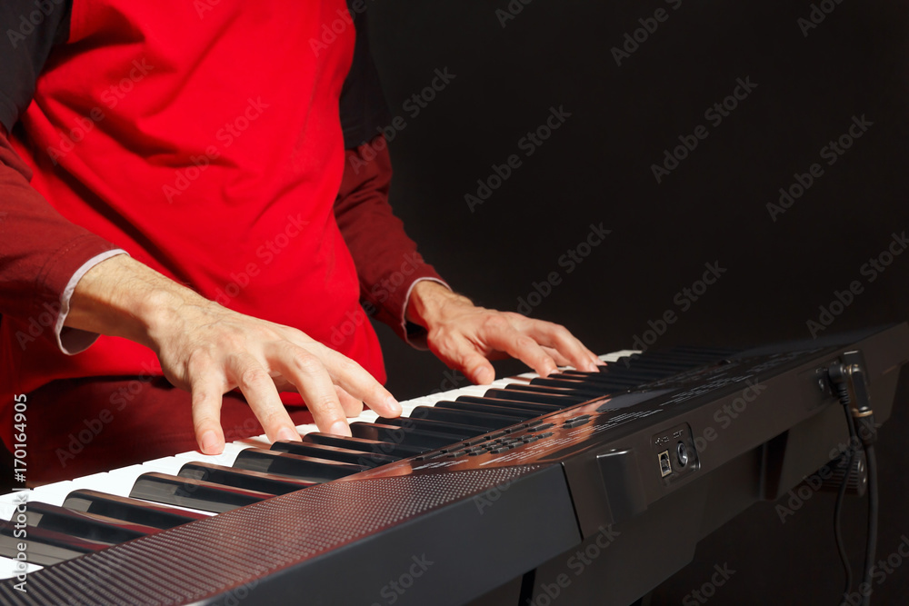 Pianist play the keys of the electronic piano on a black background