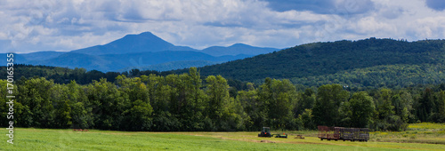 banner showing haying the fields with view of Camels Hump Mountain , Green Mountains of Vermont